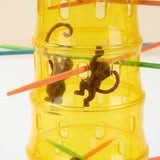 Close-up of a board game's translucent yellow plastic tower with brown monkey figures and colorful plastic sticks.