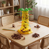 Falling Monkeys board game with a yellow plastic tree, colored sticks, brown monkeys and die on a wooden dining table.