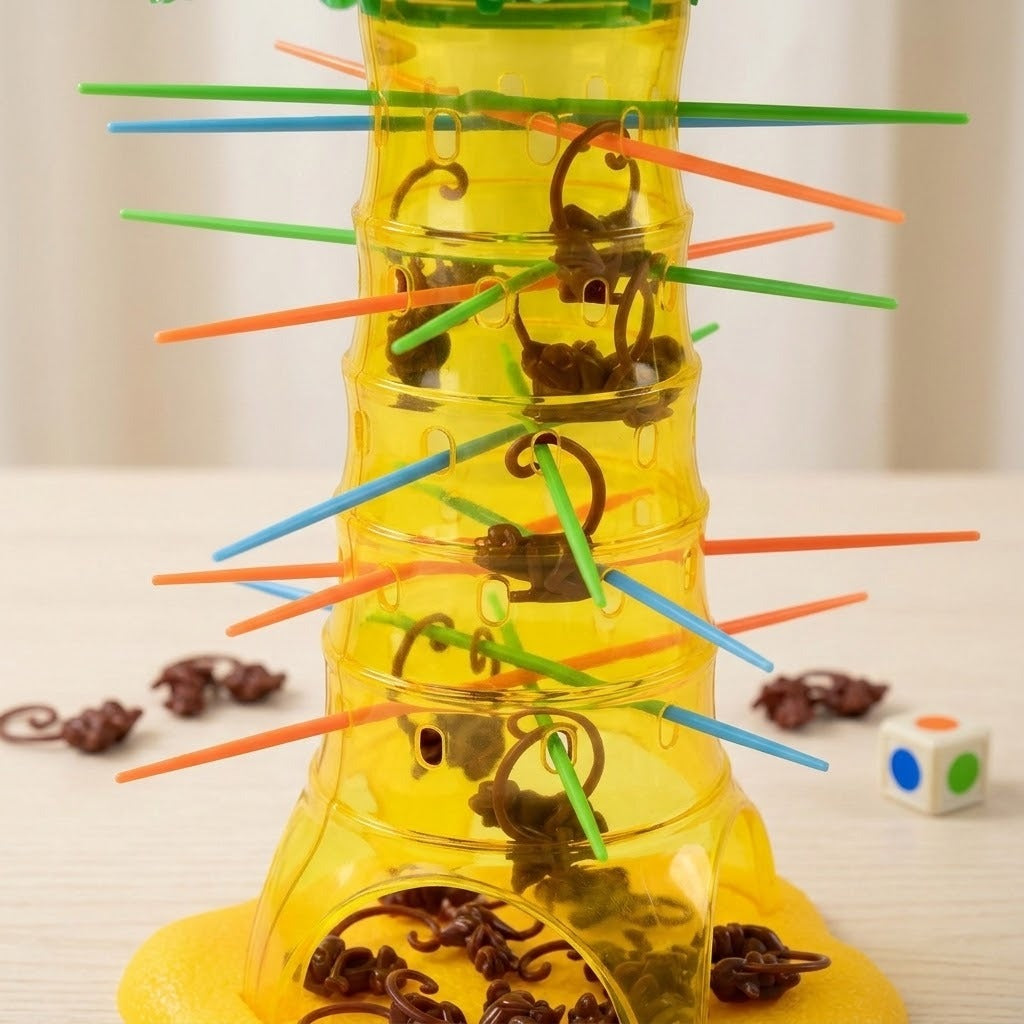 Close-up of the board game's translucent yellow plastic tree with brown monkeys hanging from colored sticks on a pale wooden table.