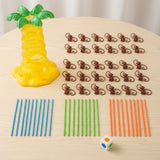 Board game components arranged on a wooden table include a yellow plastic tree, brown monkeys, blue, green and orange sticks, and die.