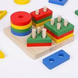 A colorful wooden children's shape-sorting toy set on a white background, featuring stacked round and square peg blocks in red, yellow, green, and blue on a natural wood base, with a separate blue rectangular piece nearby.