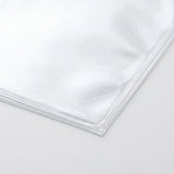 Clear card sleeves show thin layered edges and glossy corners in a close-up against a pale background.