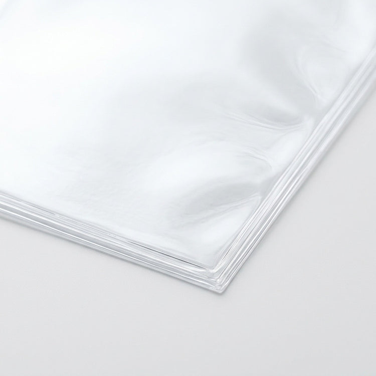 Clear card sleeves show thin layered edges and glossy corners in a close-up against a pale background.