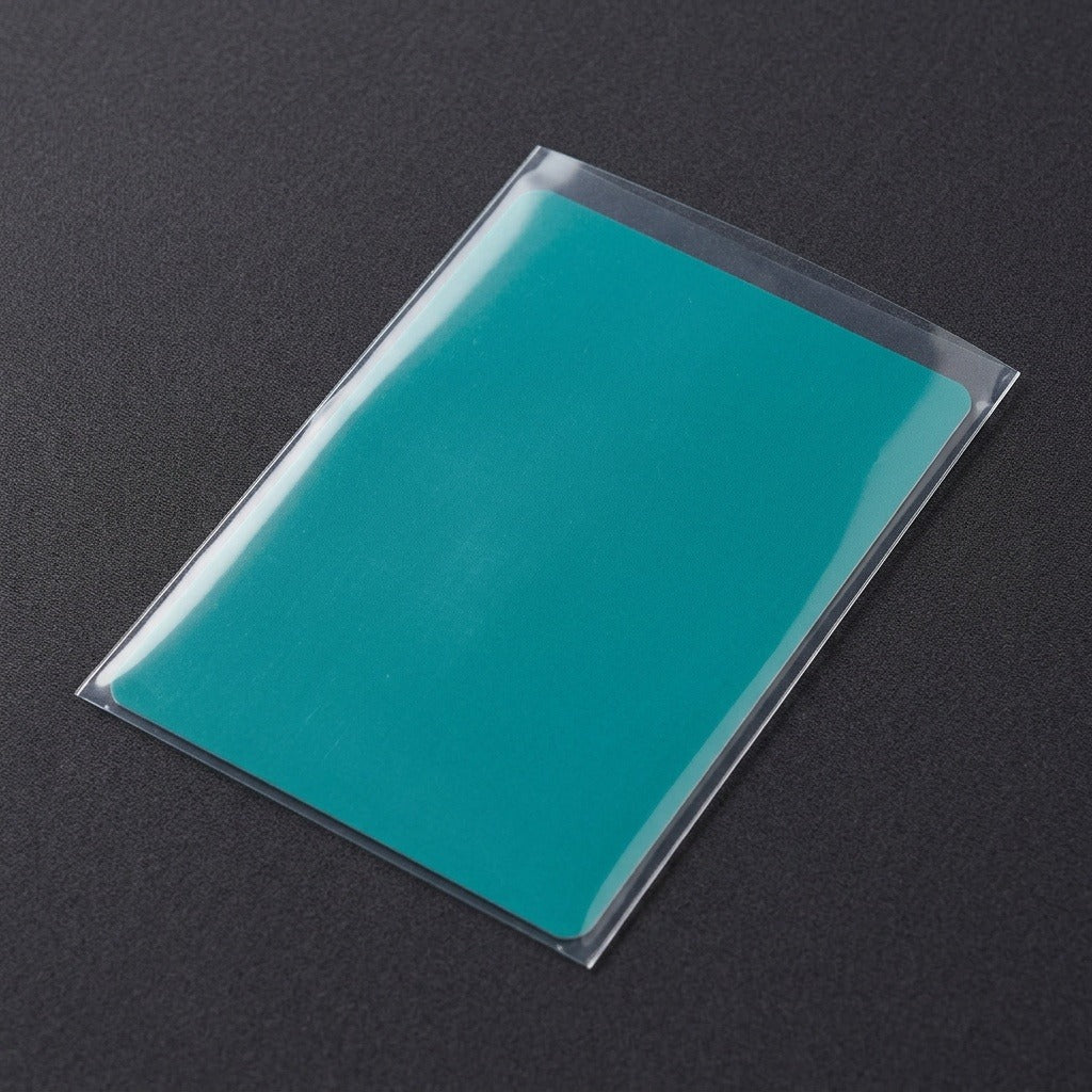 A clear card sleeve holds a teal demonstration insert on a dark textured surface.