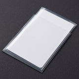 Clear plastic card sleeves hold a blank white card diagonally on a dark textured background.