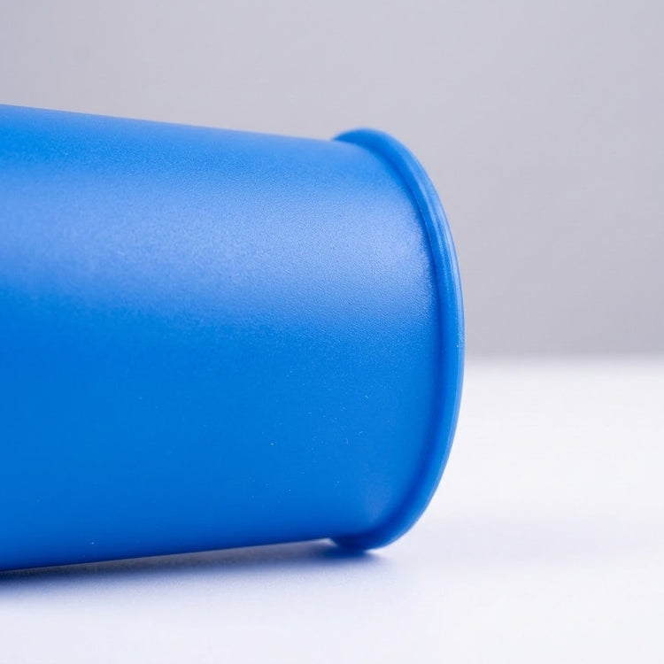 Close-up of a blue plastic cup from the cup stacking game, showing its textured surface and rounded rim against white.