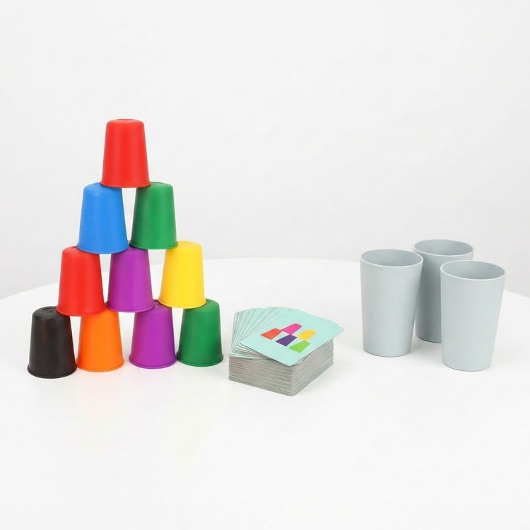 Cup stacking game with colorful plastic cups stacked in a pyramid, matching cards, and three gray cups on a white surface.