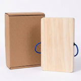 Plain wooden back of a rectangular busy board stands beside a brown cardboard box against a white background.