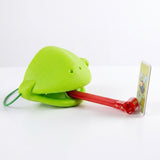 Frog tongue party game with a green mask extending its red tongue toward an upright insect target on a white surface.