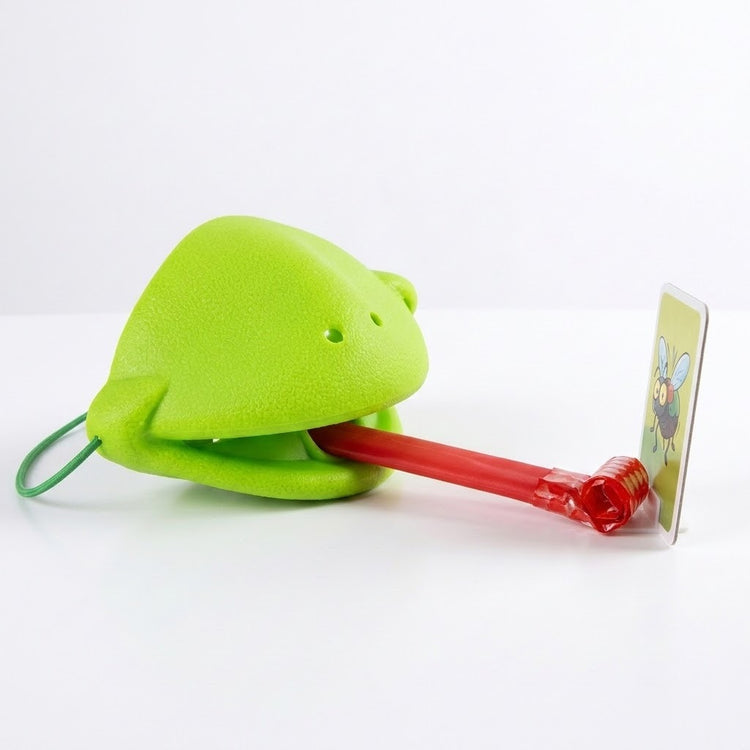 Frog tongue party game with a green mask extending its red tongue toward an upright insect target on a white surface.