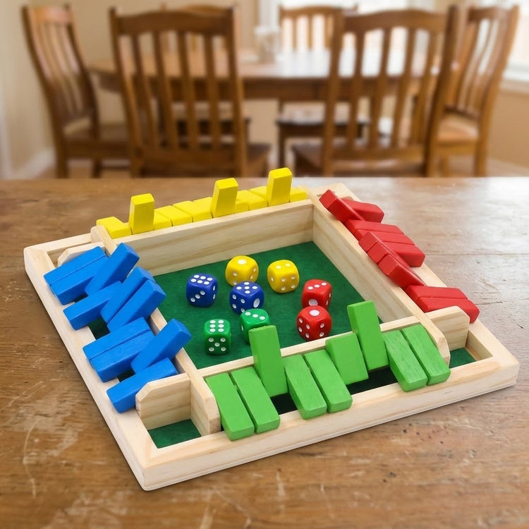 A multicolor wooden shut the box game with green felt and colored dice sits on a wooden dining table with chairs behind.