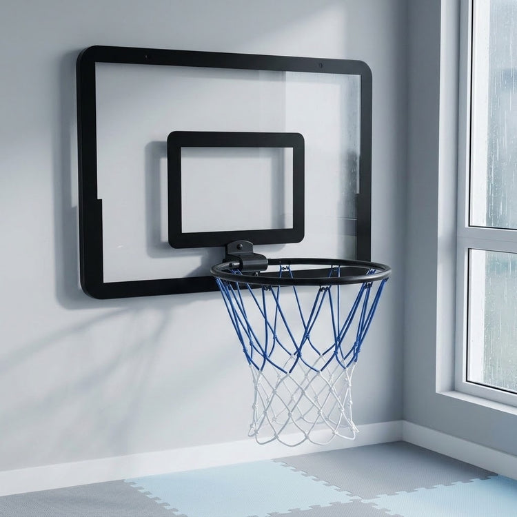 Black mini basketball hoop with a blue and white net mounted beside a window above interlocking foam floor mats.