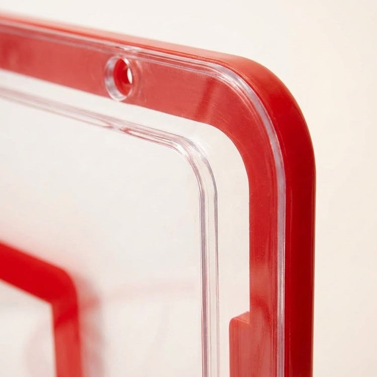 Basketball hoop backboard corner shows clear plastic, a red border, a rounded edge and a circular mounting hole against a cream background.