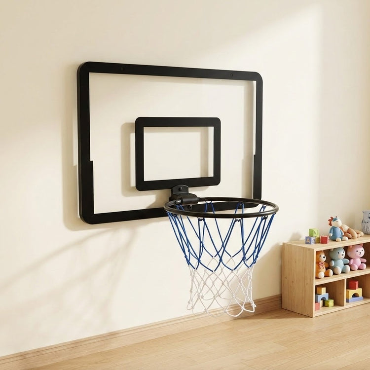 Black mini basketball hoop with blue and white net mounted on a cream playroom wall beside a wooden toy shelf.