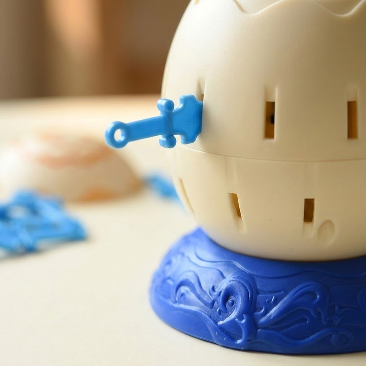 Tabletop game close-up shows a blue sword inserted into a cream barrel on a textured blue base, with loose pieces blurred behind.