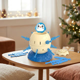 Penguin tabletop game with a cream barrel, blue swords and detached lid sits on a wooden table beside a decorated Christmas tree.