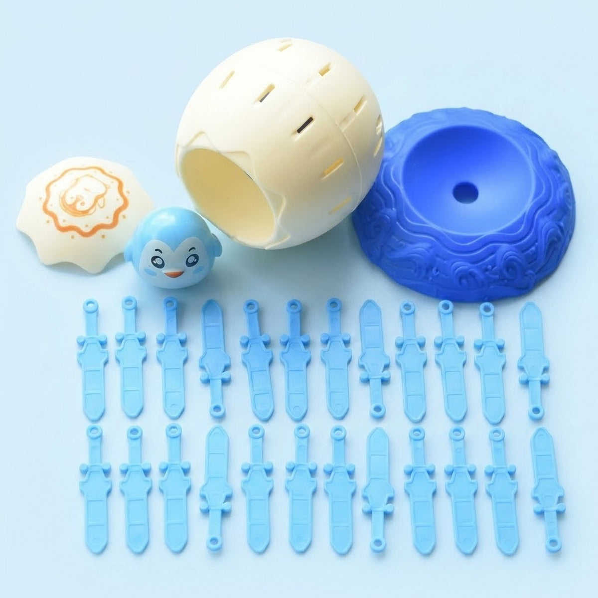Disassembled tabletop game with cream shell and lid, blue character, blue base, and light blue swords against a pale blue background.
