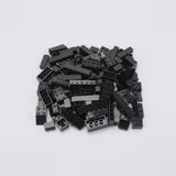 A pile of assorted black plastic building bricks in various shapes and sizes on a plain white background, from a set of 120 pieces.