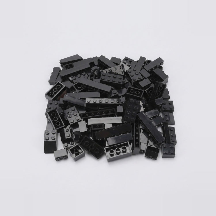A pile of assorted black plastic building bricks in various shapes and sizes on a plain white background, from a set of 120 pieces.