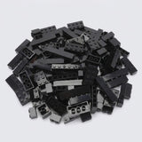A large pile of assorted black plastic building bricks in various shapes and sizes on a plain white background, from a set of 240 pieces.