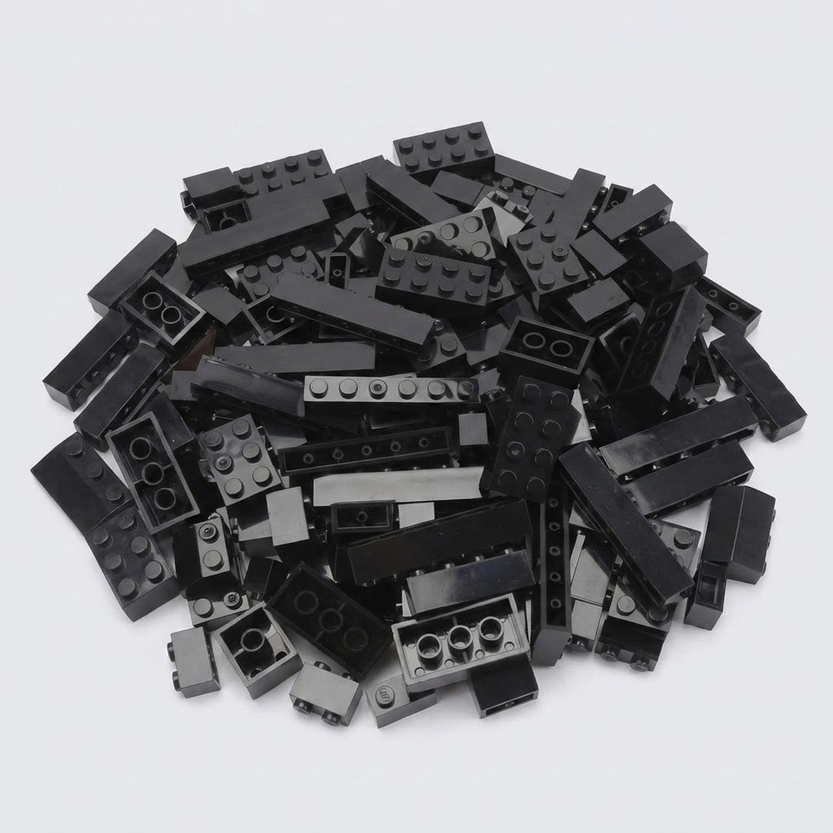 A large pile of assorted black plastic building bricks in various shapes and sizes on a plain white background, from a set of 240 pieces.