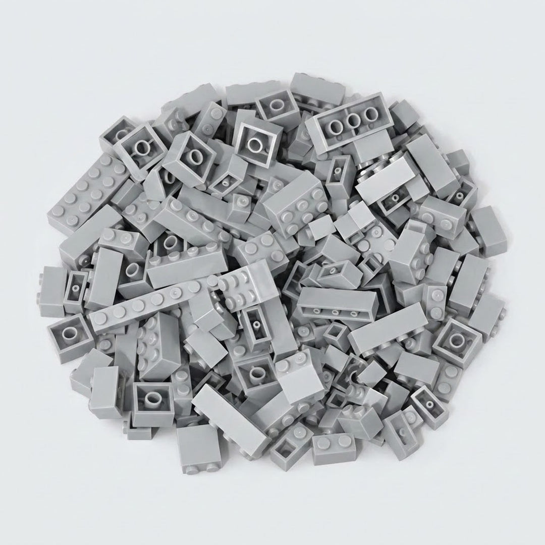 Light gray building bricks form a broad pile on a pale background, displaying round studs, smooth sides, and hollow undersides.