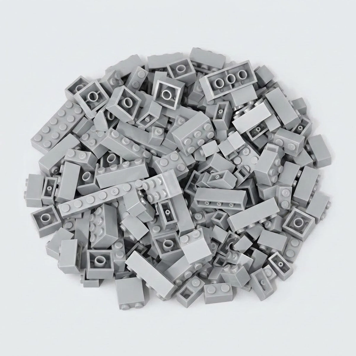 Light gray building bricks form a broad pile on a pale background, displaying round studs, smooth sides, and hollow undersides.
