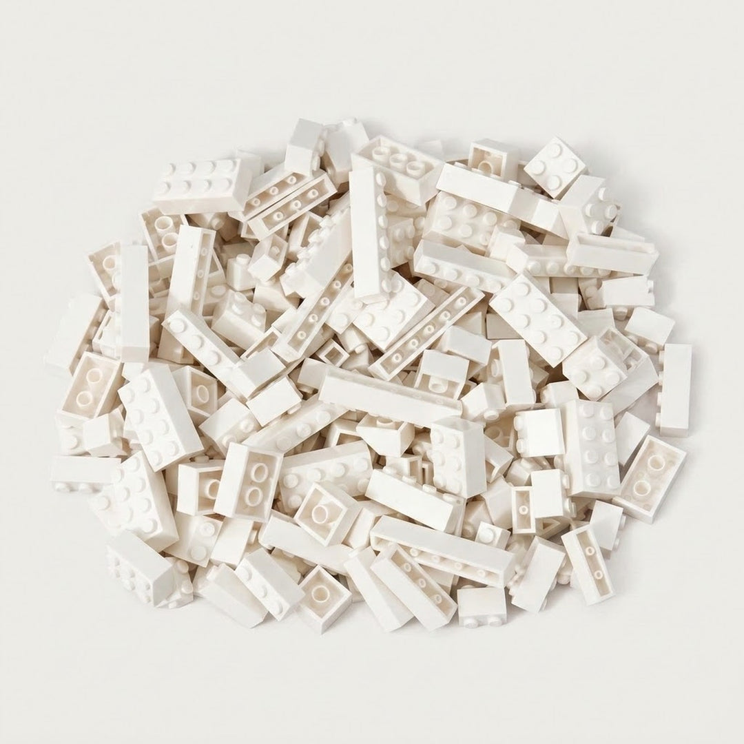 A broad pile of white building bricks rests on an off-white background, with round studs and hollow undersides visible.