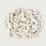 A broad pile of white building bricks rests on an off-white background, with round studs and hollow undersides visible.