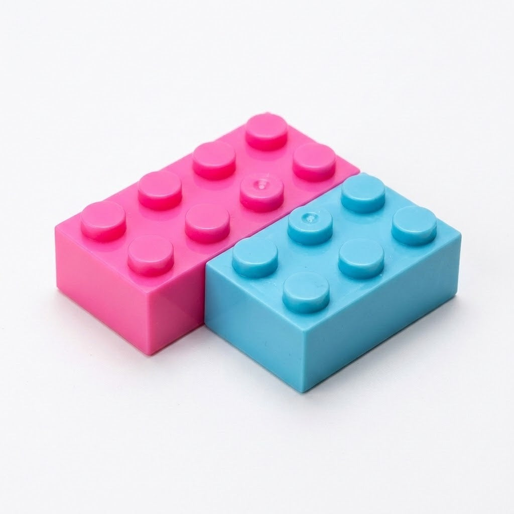 Pink and blue rectangular building bricks with round studs sit side by side on a white background.