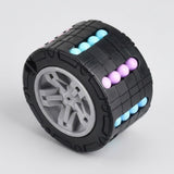 Black cylindrical fidget puzzle with a gray center and turquoise and purple beads on a light gray background.