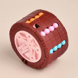 Brown cylindrical fidget puzzle with a pink center and orange, pink, and turquoise beads on a beige background.