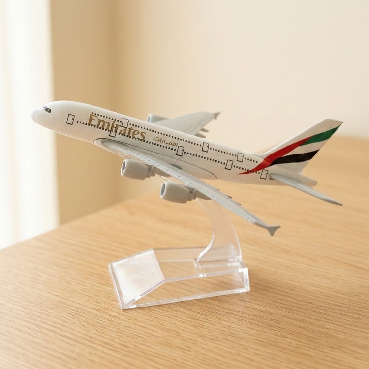 White model airplane with a multicoloured tail on a clear display stand atop a sunlit wooden table.