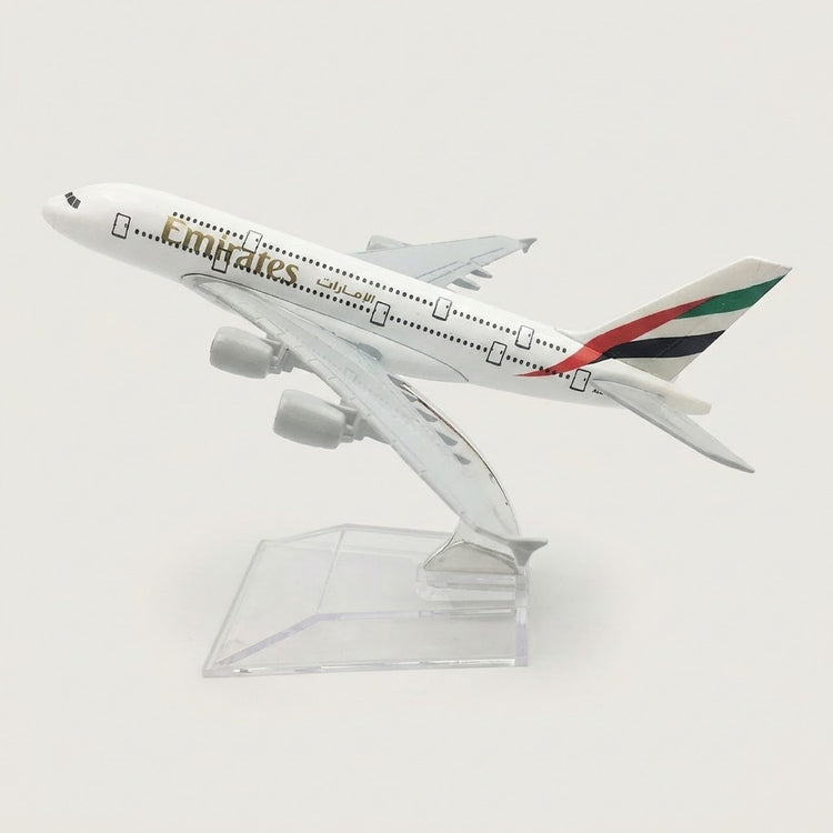 White four-engine model airplane with red, green, and black tail stripes, angled upward on a transparent display stand against a white background.