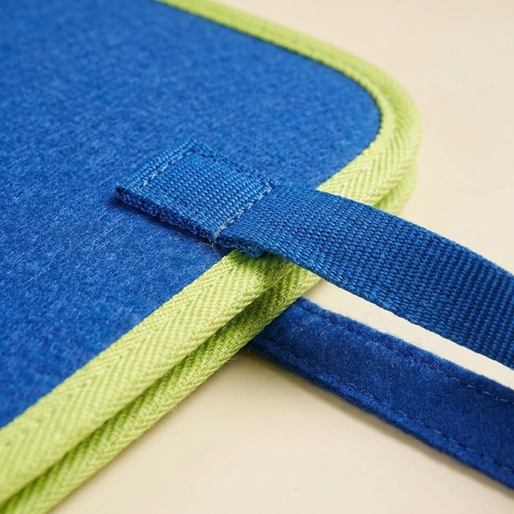 A close-up of the blue felt busy board shows its stitched woven handle and lime green edging against a cream background.