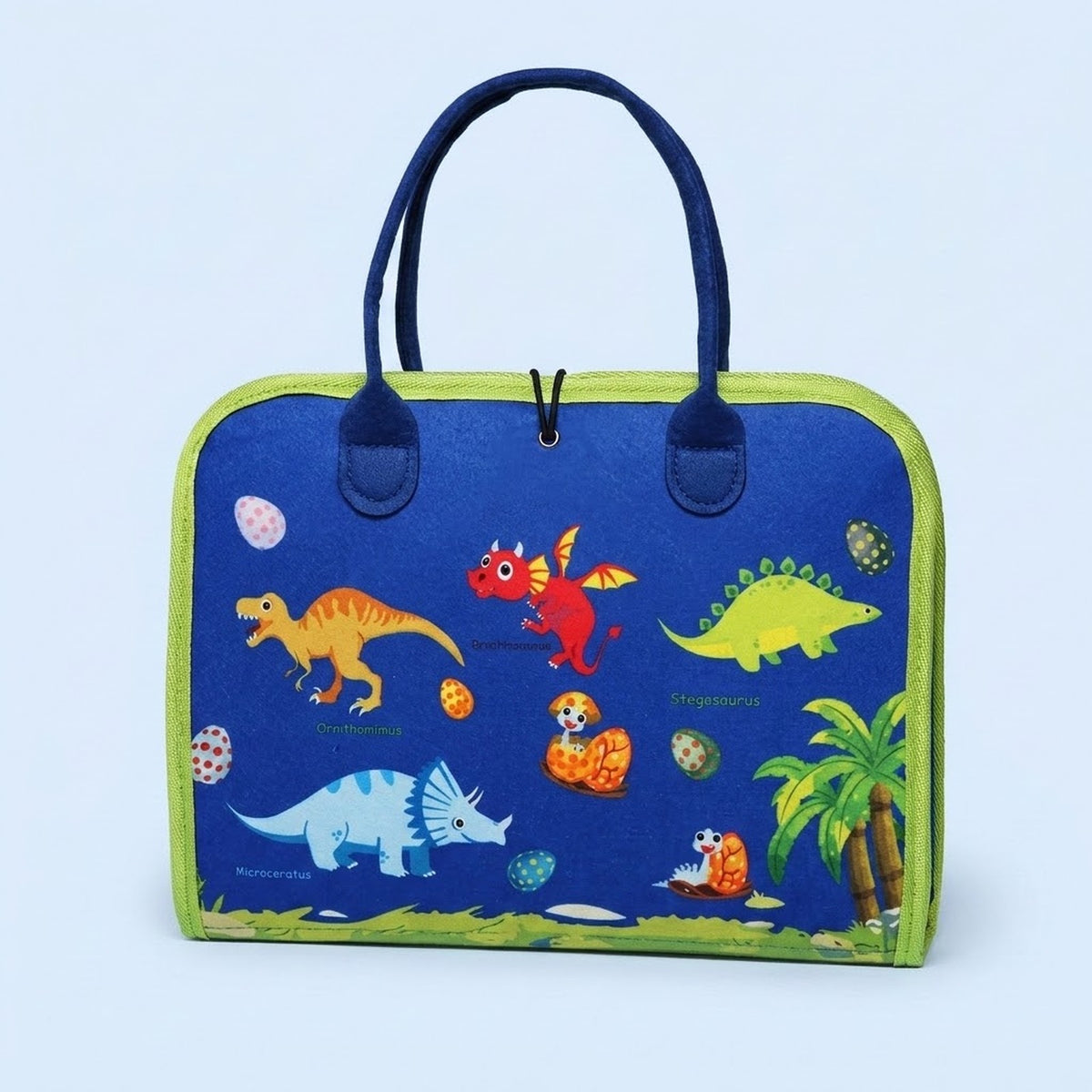 A blue fabric busy board with green trim, navy handles and colourful dinosaur illustrations stands against a pale blue background.