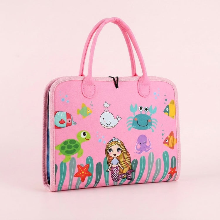 Pink fabric busy board with carry handles, a mermaid and sea creature illustrations stands closed against a pale pink background.