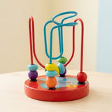 Wooden bead maze learning toy with colorful beads, turquoise and red wires, and a red elephant base on a pale wooden table.