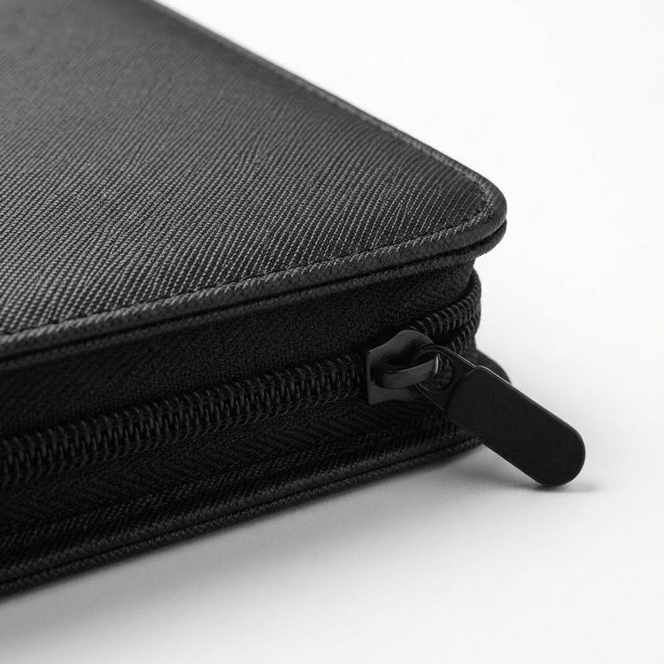 A close-up shows the black trading card binder's textured PU cover, stitched corner, and zipper pull against a white background.