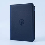 Navy blue textured trading card binder with zipper, shown closed with an embossed shield emblem on a pale blue background.