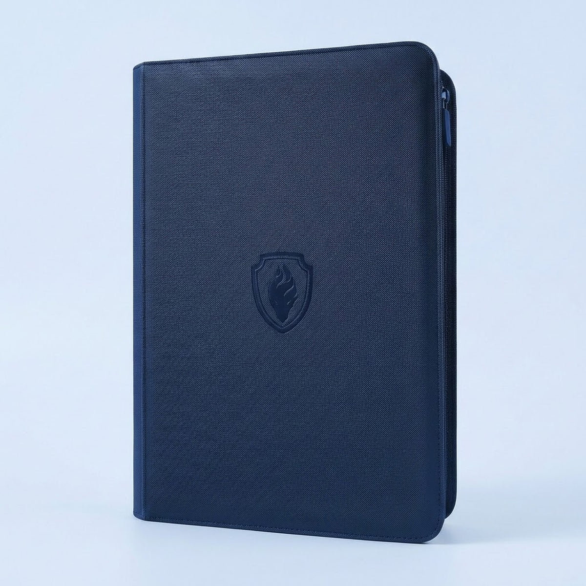 Navy blue textured trading card binder with zipper, shown closed with an embossed shield emblem on a pale blue background.