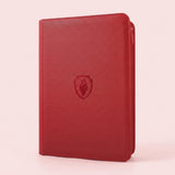 A red trading card binder with a textured PU cover and closed zipper stands upright against a pale pink background.
