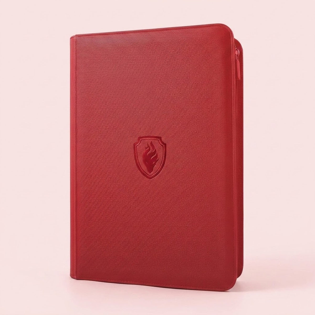 A red trading card binder with a textured PU cover and closed zipper stands upright against a pale pink background.