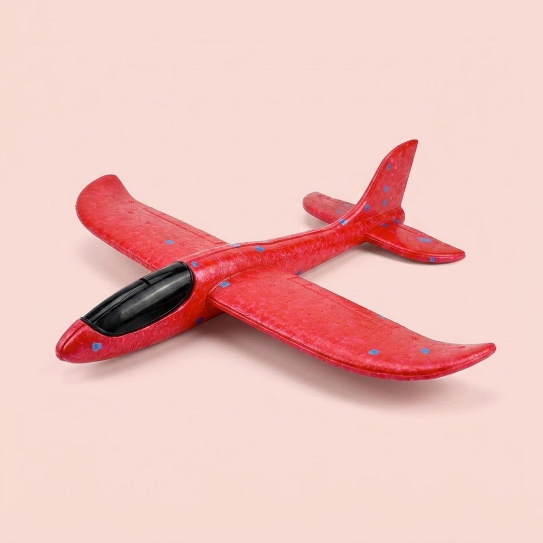 Red foam glider for the airplane launcher toy, with blue speckles and a black cockpit, shown against a pale pink background.