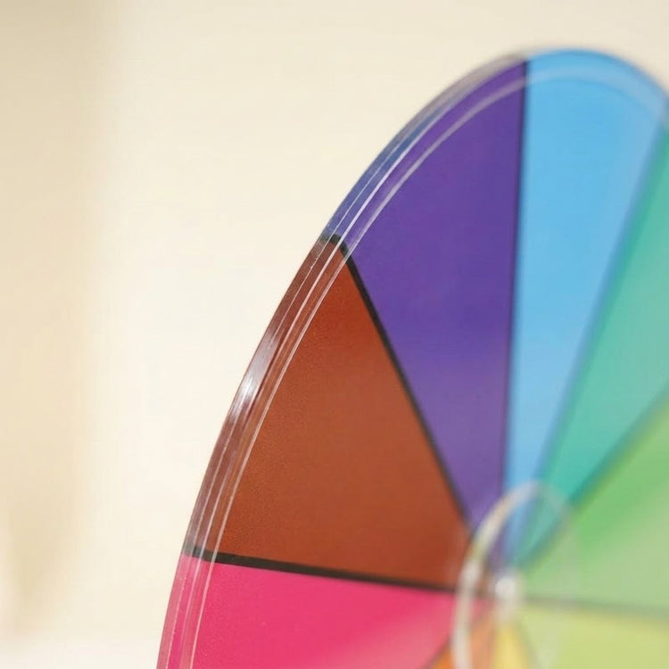 A close-up shows the clear acrylic edge and coloured segments of the prize wheel against a pale background.