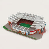 An assembled 3d stadium puzzle with white roof supports, red seating, a green pitch and gray base stands against an off-white background.
