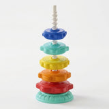A plastic stacking toy has five colorful discs spaced along a white spiral post above a mint green base against white.