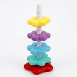 A plastic stacking toy has yellow, purple, blue and mint flower-shaped pieces along a white spiral post on a red base against white.
