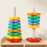 Two colorful plastic stacking toy towers with white spiral posts and red bases stand on a pale wooden shelf against a cream wall.