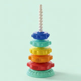 A stacking toy with blue, mint, yellow, orange and red rings on a white spiral post stands against a pale mint background.
